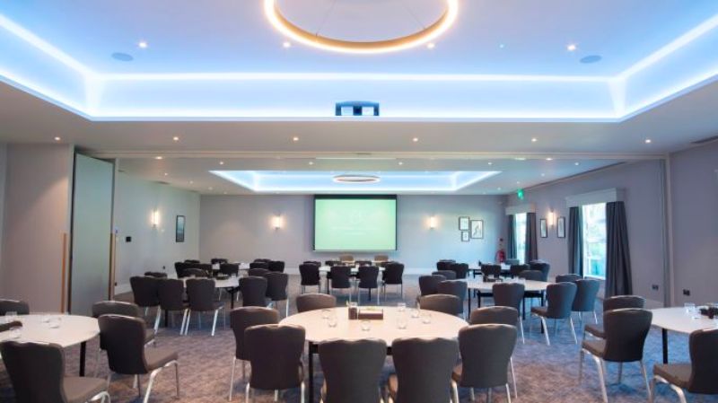 Conference Venue Nottingham, tables and chairs laid out in groups in front of a presentation screen